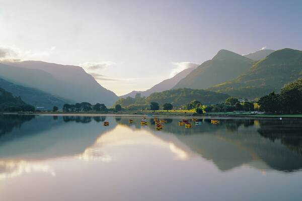 A peaceful view of Llyn Padarn lake with calm waters reflecting the surrounding mountains.