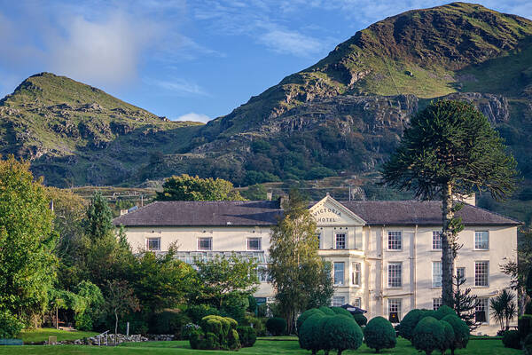 A view of the Royal Victoria Hotel in Snowdonia surrounded by lush gardens and mountains.